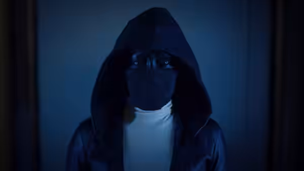 Sister Night (Regina King) in black hooded jacket standing in dim blue light