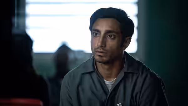 Nasir Khan (Riz Ahmed) gazes intently in a brightly lit room