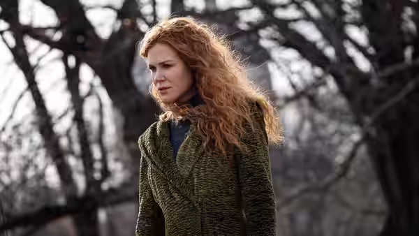 Grace Fraser (Nicole Kidman) in a green coat walks among bare trees