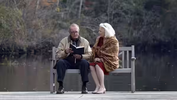 Older Noah (James Garner) reading beside Older Allie (Gena Rowlands) on a bench