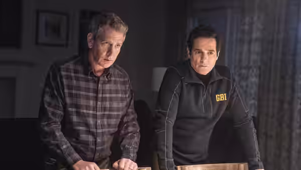two men standing side by side in a dimly lit room