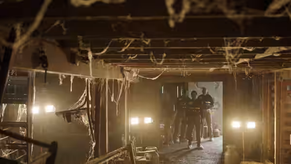 a group of people standing in a derelict building with work lights