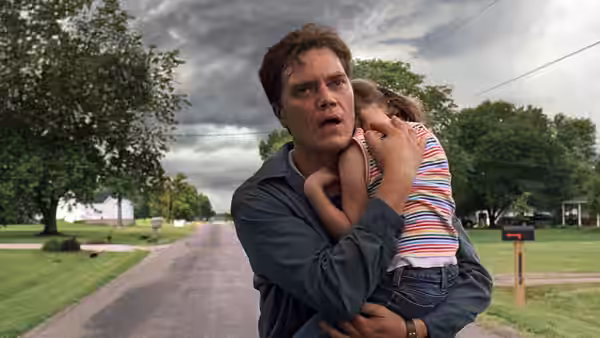 Curtis LaForche (Michael Shannon) carries his daughter Hannah on a suburban street under stormy skies
