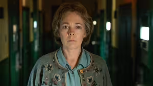 Susan Edwards (Olivia Colman) standing in a green institutional corridor