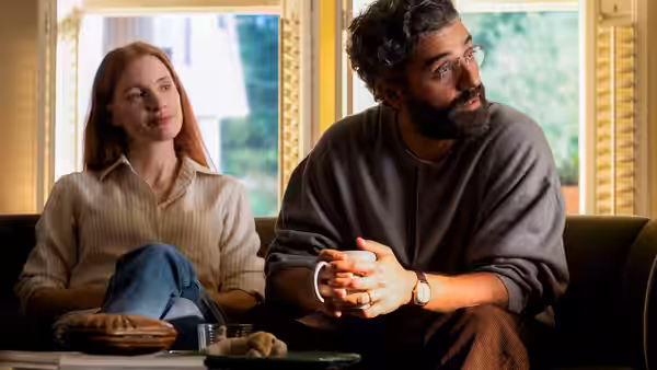 Mira (Jessica Chastain) and Jonathan (Oscar Isaac) seated side by side on a couch