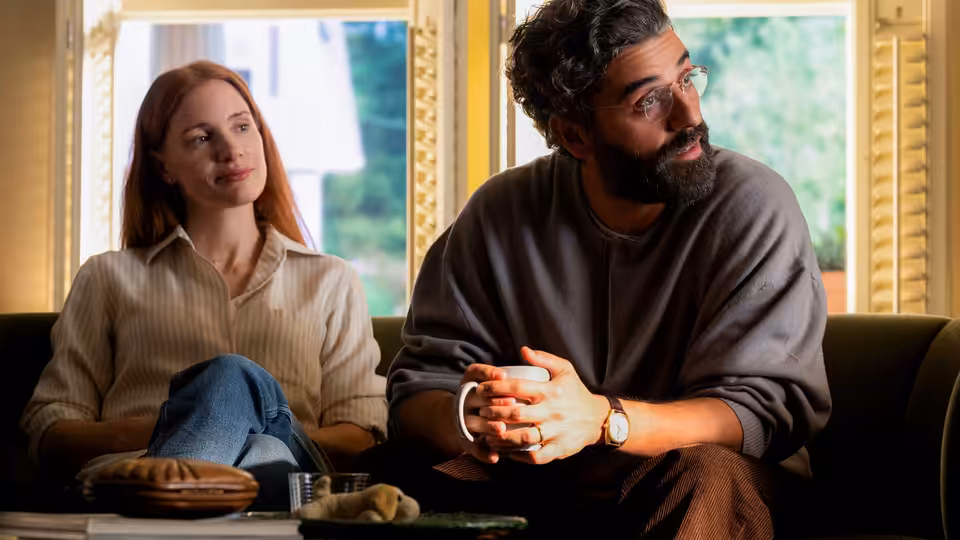 Mira (Jessica Chastain) and Jonathan (Oscar Isaac) seated side by side on a couch