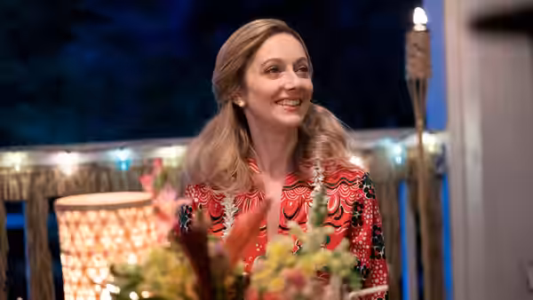 Dorothy Hunt (Lena Headey) smiles on a night porch with string lights