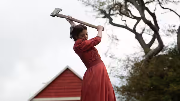 Pearl (Mia Goth) raising an axe in a field