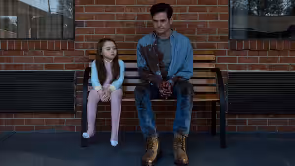 A man and girl sit on a bench holding a bouquet of flowers