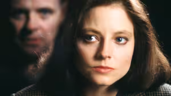 Clarice Starling (Jodie Foster) in close-up with a blurred face behind her