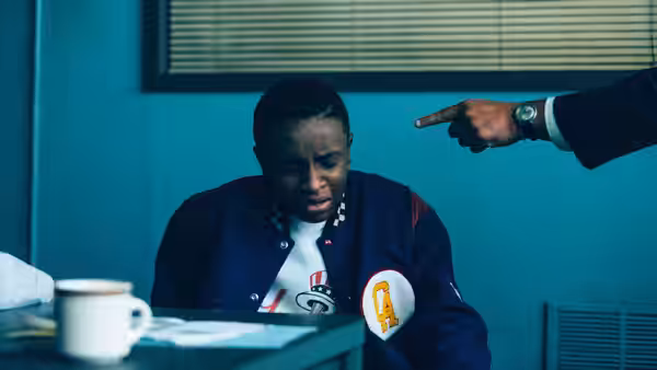 Young man in varsity jacket seated at a table