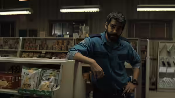 Sheriff Hassan (Rahul Kohli) standing behind the counter in a store