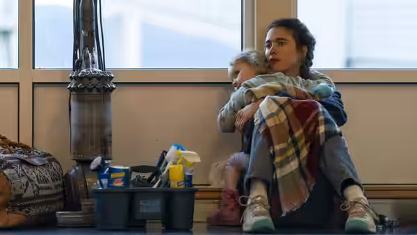 Alex (Margaret Qualley) holding Maddy on her lap amid cleaning supplies