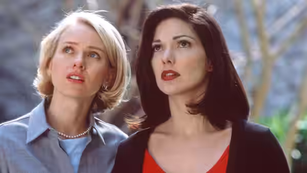 blonde woman in blue shirt standing beside brunette woman outdoors