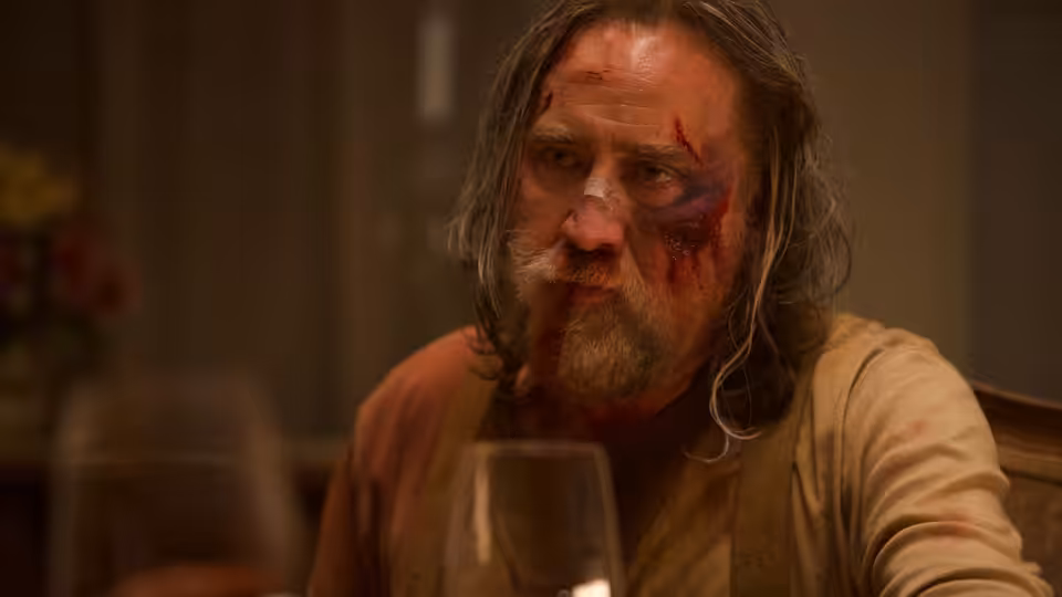 Rob Feld (Nicolas Cage), bruised and bloodied, sits at a restaurant table