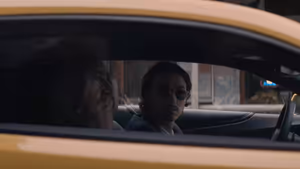 Rob Feld and Amir sit together inside a yellow car