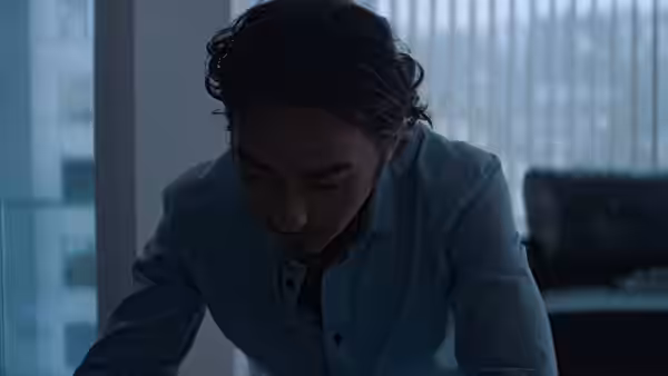 Amir (Alex Wolff) leans forward in a blue-lit modern office