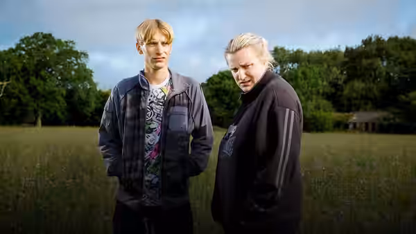 Kurtan (Charlie Cooper) and Kerry Mucklowe (Daisy May Cooper) in a grassy field