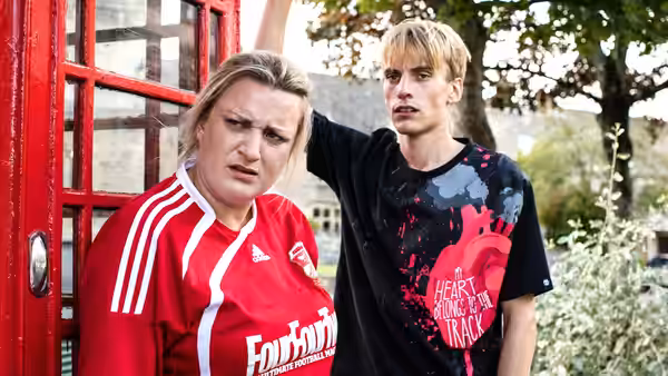 Kerry Mucklowe (Daisy May Cooper) and Kurtan (Charlie Cooper) beside a red phone box