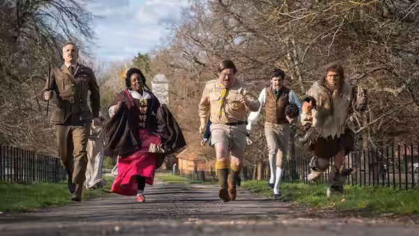 The Captain (Ben Willbond), Kitty (Lolly Adefope) and others run along a park road