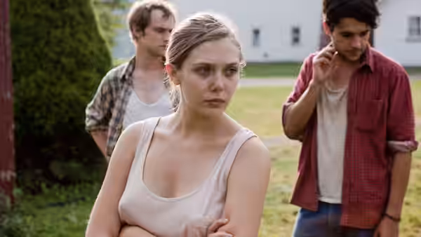 Martha (Elizabeth Olsen) stands with arms crossed while two men watch