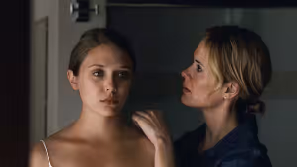 Martha (Elizabeth Olsen) stands while Lucy (Sarah Paulson) places a hand on her shoulder