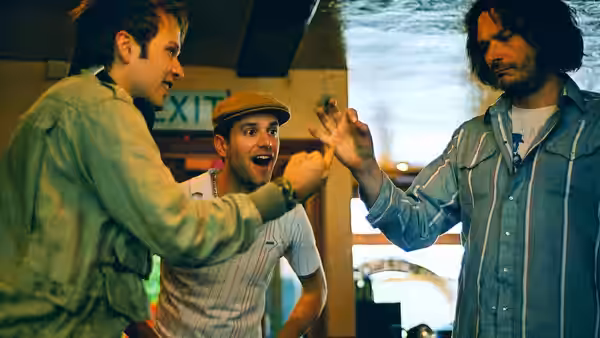 Three men gesturing at each other inside a bar near an exit sign