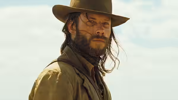 Charlie Burns (Guy Pearce) stands outdoors wearing a broad-brimmed hat