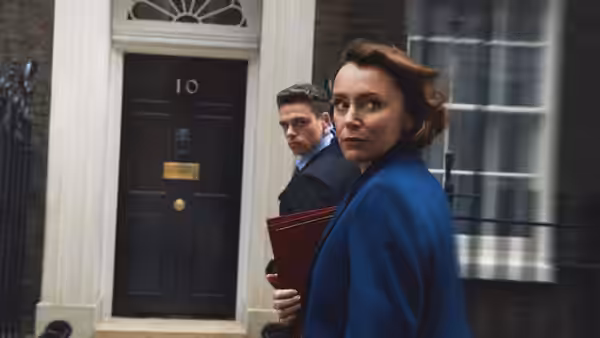 Julia Montague (Keeley Hawes) carrying a red folder walking past number 10 with David Budd (Richard Madden) following