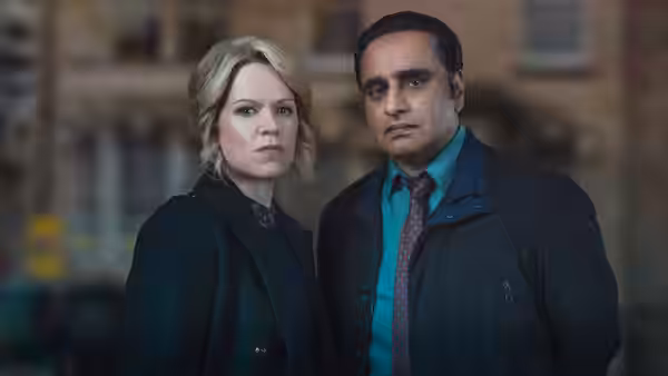 A blonde woman and DS Sunny Khan (Sanjeev Bhaskar) standing side by side at dusk