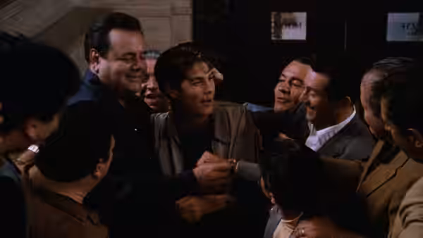Tommy DeVito (Joe Pesci) embraced by associates in a hallway