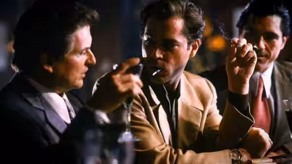 Henry Hill (Ray Liotta) holding a cigar at a dimly lit table