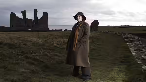 DCI Vera Stanhope (Brenda Blethyn) in a field near ruined stone walls by the sea