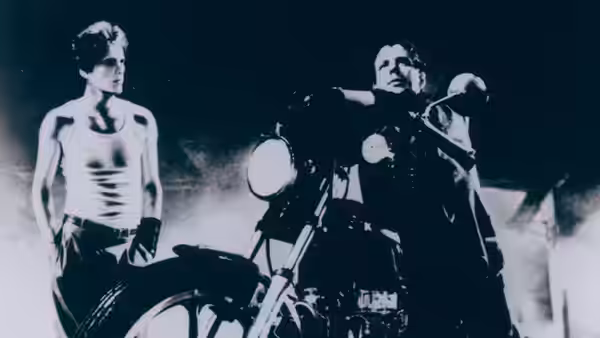 The Motorcycle Boy (Mickey Rourke) sits on a motorcycle next to Rusty James (Matt Dillon)