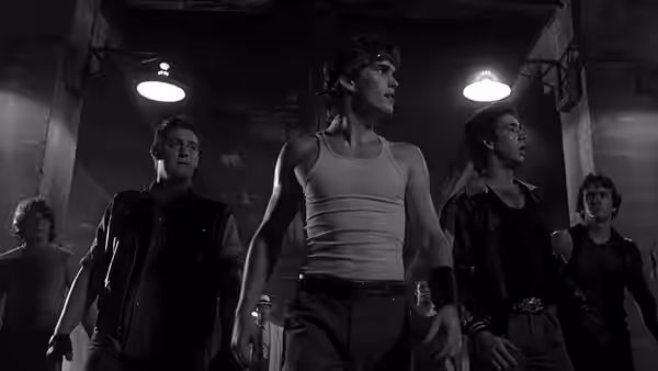 Rusty James (Matt Dillon) walks ahead of several young men in a dark industrial space