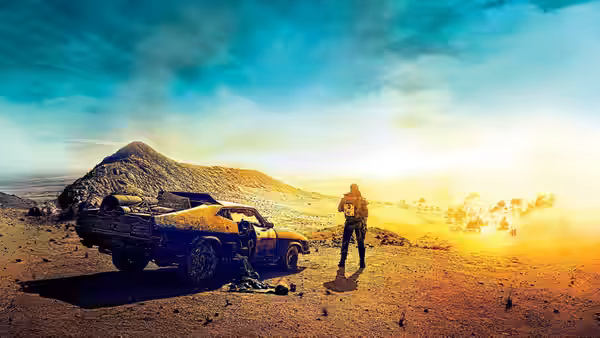 Max (Tom Hardy) stands beside a wrecked car in the desert