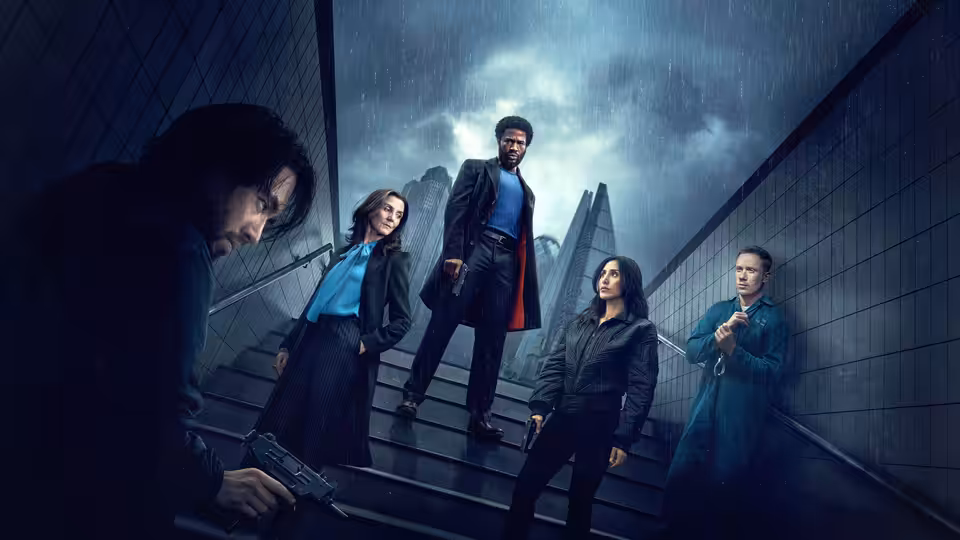Five people stand on rain-slicked outdoor stairs with one aiming a pistol