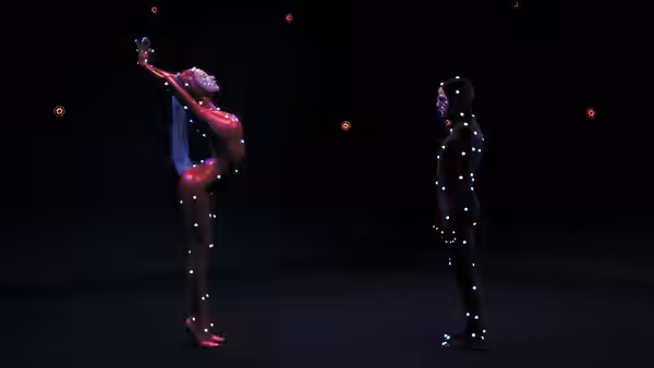 performer in glowing red bodysuit arches back while another stands nearby in dark space