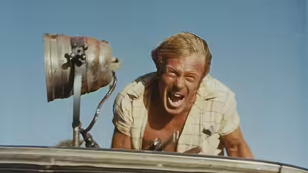 John Grant (Gary Bond) leans from a car roof shouting with mouth open