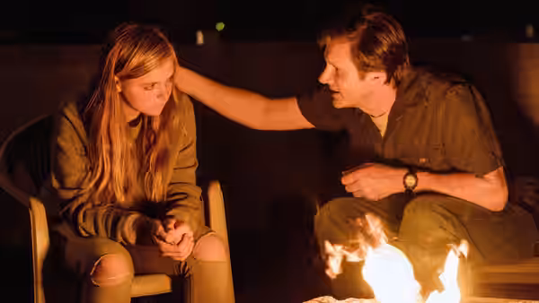 Kayla (Elsie Fisher) and Mark (Josh Hamilton) talking by a campfire at night