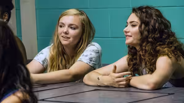 Kayla (Elsie Fisher) and Olivia (Emily Robinson) talking at a table
