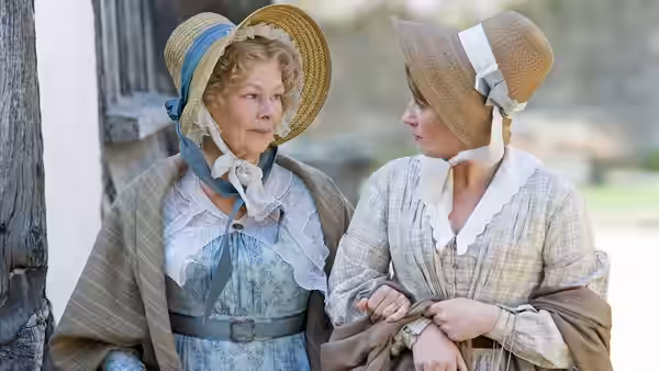 Miss Matilda Jenkyns (Judi Dench) speaking with another woman near a wooden building