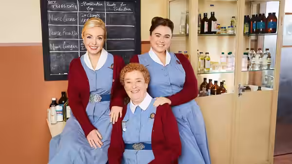 Three nurses posing together beside a chalkboard in a clinic