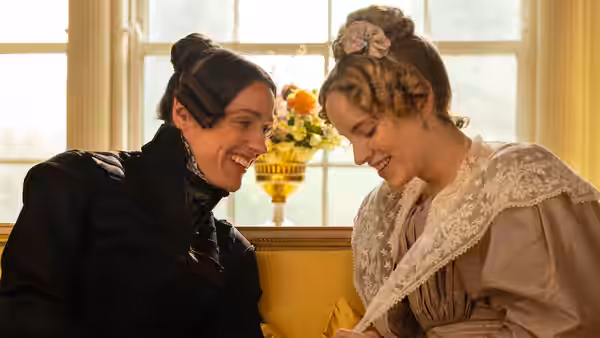 Anne Lister (Suranne Jones) and Ann Walker (Sophie Rundle) smiling closely indoors by a window