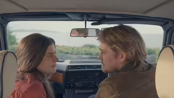 Couple sitting in a car looking at each other across the seats