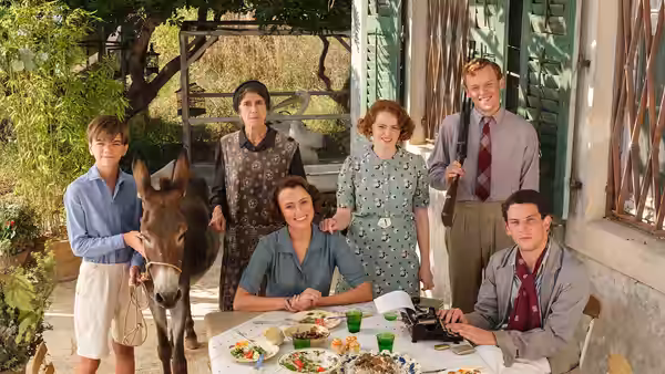 Group gathers around an outdoor table with a donkey