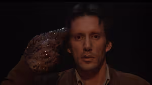 Max Renn (James Woods) staring ahead with a grotesque hand on his temple