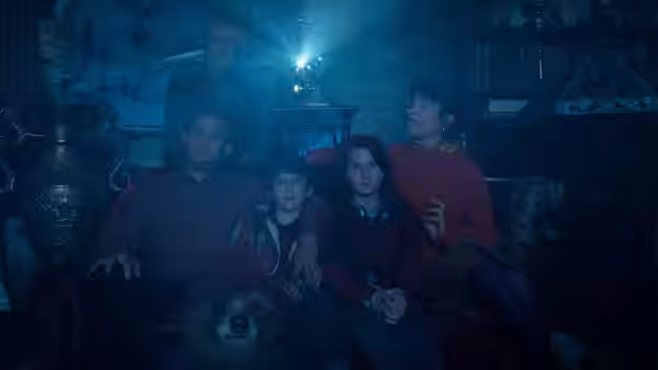 The Brown family sit together in a dark room, watching something offscreen