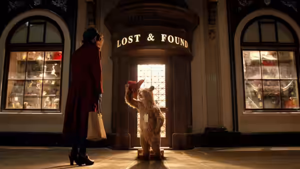 Paddington waves to a woman beneath the Lost and Found sign