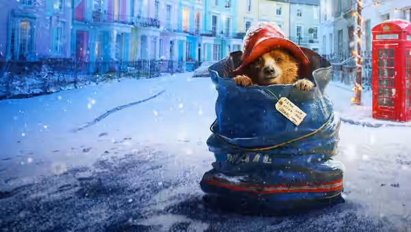 Paddington peeks from a suitcase on a snowy London street